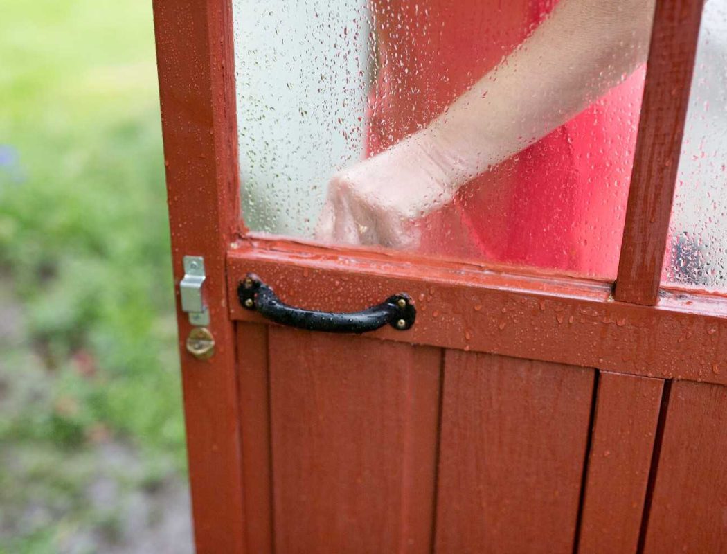 hand-opens-the-red-shed-door-on-rainy-day-2026-03-09-09-21-27-utc (1)